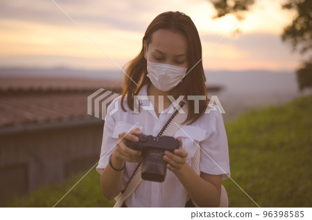 Young woman checking her camera in golden hour Young woman checking her camera in golden hour 96398585