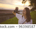 Happy young woman enjoy using camera in golden hour 96398587