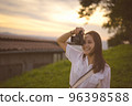 Young woman enjoying when her using camera ,golden hour in background 96398588