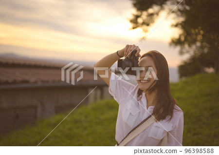 Young woman enjoying when her using camera ,golden hour in background 96398588
