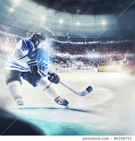 The arena of a hockey rink, a hockey player hits a hockey stick with a swing on the puck The arena of a hockey rink, a hockey player hits a hockey stick with a swing on the puck 96398752