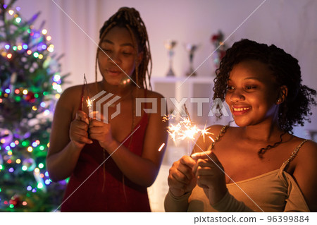 Two African women spend Christmas together and hold cold fires in their hands. Two African women spend Christmas together and hold cold fires in their hands. 96399884