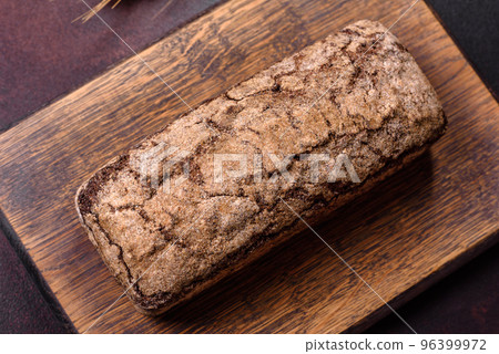A loaf of brown bread with grains of cereals on a wooden cutting board A loaf of brown bread with grains of cereals on a wooden cutting board 96399972