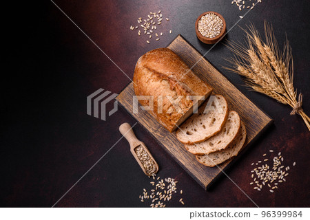 A loaf of brown bread with grains of cereals on a wooden cutting board A loaf of brown bread with grains of cereals on a wooden cutting board 96399984