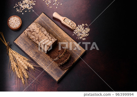 A loaf of brown bread with grains of cereals on a wooden cutting board A loaf of brown bread with grains of cereals on a wooden cutting board 96399994