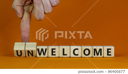Welcome or unwelcome symbol. Businessman turns wooden cubes and changes the word unwelcome to welcome. Beautiful orange table, orange background. Welcome or unwelcome and business concept. Copy space. Welcome or unwelcome symbol. Businessman turns wooden cubes and changes the word unwelcome to welcome. Beautiful orange table, orange background. Welcome or unwelcome and business concept. Copy space. 96400877
