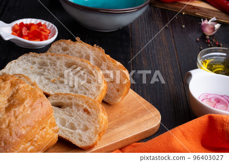 fresh ciabatta bread  with blue bowl and ingredients served at dark wooden table. meditarranean cuisine. close up 96403027