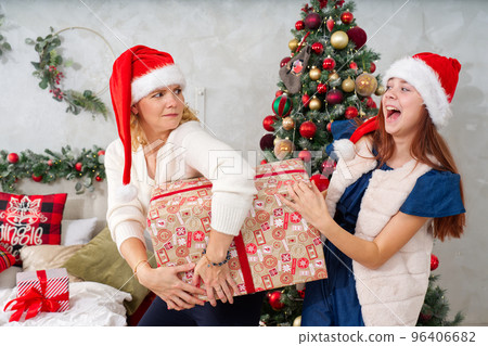 Smiling mother gives her daughter a christmas present. Happy family sharing joy with each other. 96406682