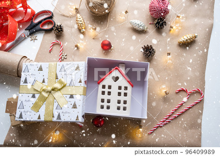 Key to house with keychain on cozy home in gift box with Christmas decor packaging. Pack present for New Year, Christmas. Building, project, moving to new house, mortgage, rent, purchase real estate 96409989