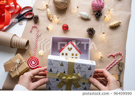 Key to house with keychain on cozy home in gift box with Christmas decor packaging. Pack present for New Year, Christmas. Building, project, moving to new house, mortgage, rent, purchase real estate 96409990