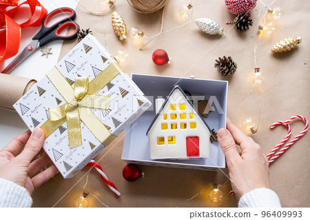 Key to house with keychain on cozy home in gift box with Christmas decor packaging. Pack present for New Year, Christmas. Building, project, moving to new house, mortgage, rent, purchase real estate 96409993