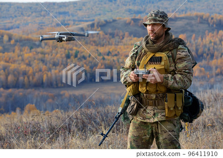 An artillery spotter or military observer launches a drone into the sky for reconnaissance in enemy territory. An artillery spotter or military observer launches a drone into the sky for reconnaissance in enemy territory. 96411910
