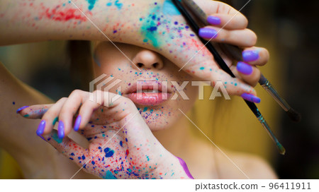 Woman artist with a drops of paints on the face and hands. 96411911