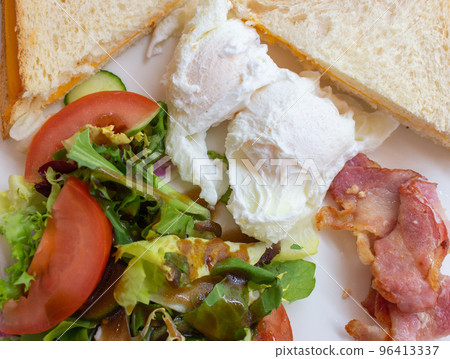 English breakfast top view. Toasts with cheese, fried bacon, fresh salad and eggs. Morning meal close up. Tasty food concept. Delicious breakfast in restaurant. Eggs with vegetables and roasted ham English breakfast top view. Toasts with cheese, fried bacon, fresh salad and eggs. Morning meal close up. Tasty food concept. Delicious breakfast in restaurant. Eggs with vegetables and roasted ham 96413337