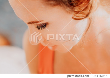 outdoor portrait of beautiful young brunette woman in red sport suit with red headband on the beach at sunrise near the sea. The concept of an travel, active and healthy life in harmony with nature. 96416056