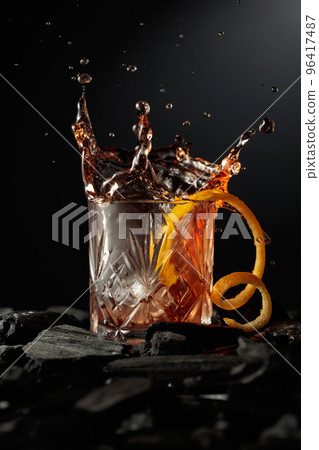 Piece of ice falls into the glass with a cocktail. 96417487
