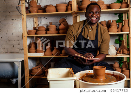 happy African American businessman potter male owner making clay sculpture pot cup vase at workbench in workshop studio . creativity and creative china shop merchant 96417783