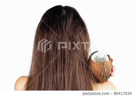 sexy nude indian woman applying coconut oil from the bottle and cap to dark brunette long hair in a hand on white isolate back view 96417834