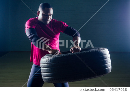 muscular shirtless young african american man in sportswear tire exercising with tyre in gym on a black background in the studio workshop 96417918