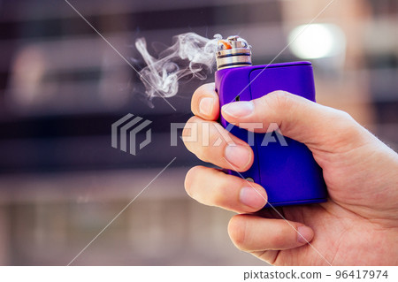 purple vape in a man's hand on a modern background purple vape in a man's hand on a modern background 96417974