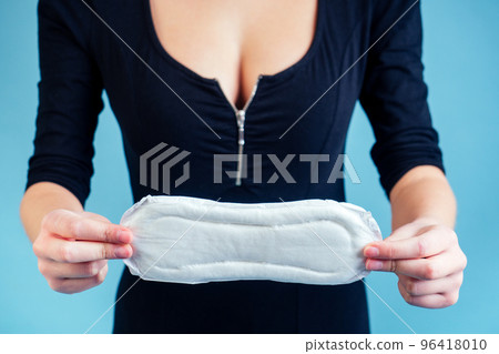 white sanitary napkin in the hands of a girl on a blue background white sanitary napkin in the hands of a girl on a blue background 96418010