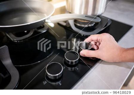 Male hand turning switch knob on gas stove Male hand turning switch knob on gas stove 96418029