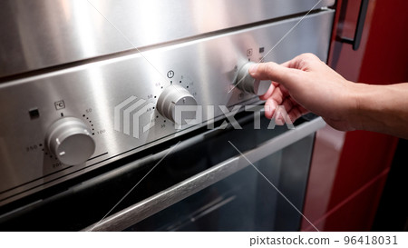 Male hand turning temperature knob of oven Male hand turning temperature knob of oven 96418031