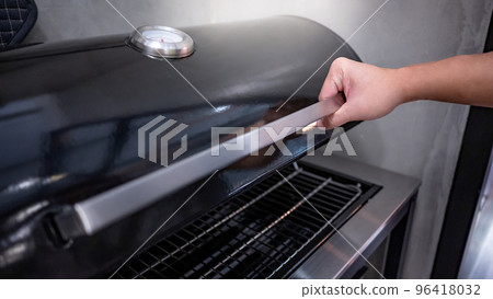 Male hand opening outdoor gas barbecue (BBQ) grill Male hand opening outdoor gas barbecue (BBQ) grill 96418032