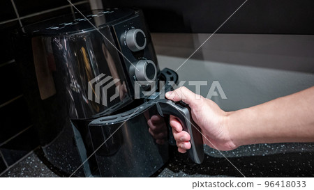Male hand holding an electric air fryer handle Male hand holding an electric air fryer handle 96418033