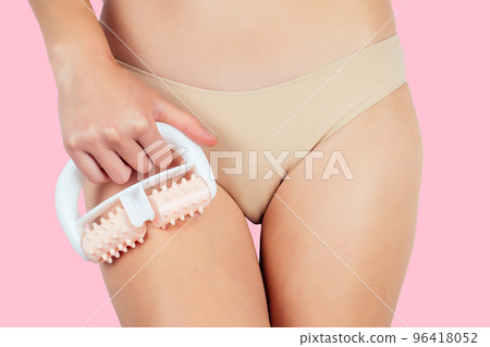 Anti-cellulite massage.Woman in beige panties massaging thigh massage roller her leg hips and butt ass on a pink background in the studio.slimming for the beach sea summer season 96418052