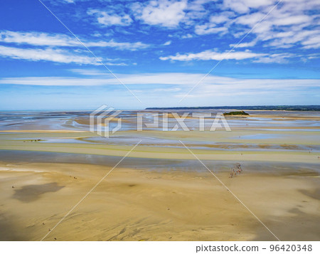 Groups of tourists walking on the colourful sand flats surrounding Le Mont Saint Michel during low tide, Normandy, Northern France 96420348