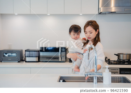 Mother doing housework while holding baby 96421590