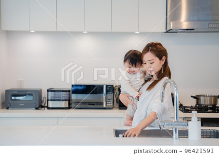Mother doing housework while holding baby Mother doing housework while holding baby 96421591