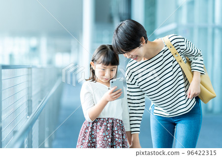 父母和孩子看著智能手機的屏幕。 96422315