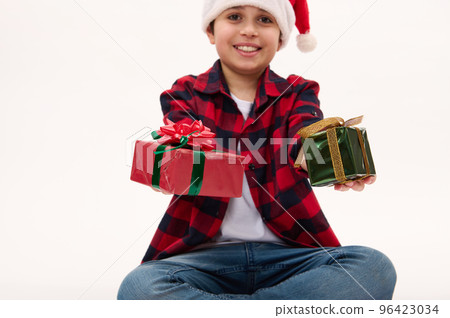 Selective focus on beautiful happy presents for Christmas or New Year, in the hands of a blurred charming preteen boy wearing Santa, isolated over white background with copy ad space. Boxing Day Selective focus on beautiful happy presents for Christmas or New Year, in the hands of a blurred charming preteen boy wearing Santa, isolated over white background with copy ad space. Boxing Day 96423034