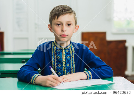 Portrait of a boy in a blue embroidered traditional Ukrainian shirt, boy holding a pen in his hand. 96423683