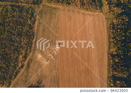 Large agricultural machinery works on Ukrainian fields, cultivation of Carpathian fields before sowing of grain crops, fields are located near the forest. 96423803