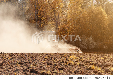 In the autumn, a farmer pulls harrows with a modern tractor and sows a field with beets. Sowing campaign on agricultural land during tillage. In the autumn, a farmer pulls harrows with a modern tractor and sows a field with beets. Sowing campaign on agricultural land during tillage. 96423814