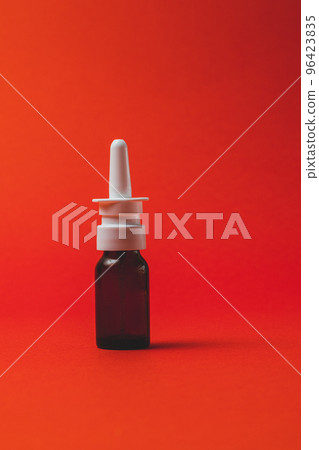 nasal spray in dark bottle with nozzle on red background. nasal spray in dark bottle with nozzle on red background. 96423835