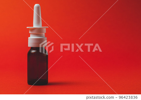 nasal spray in dark bottle with nozzle on red background. 96423836