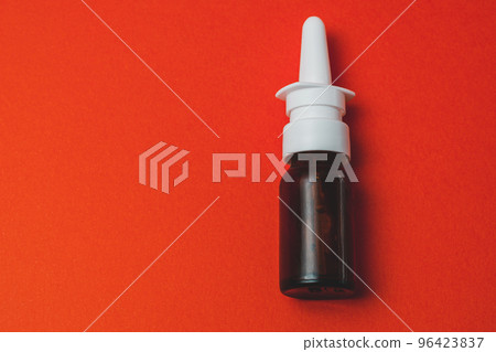 nasal spray in dark bottle with nozzle on red background. 96423837