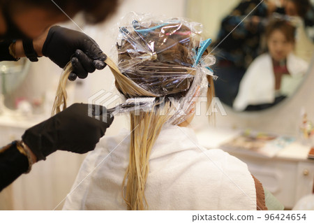 Male hairdresser applying drug to woman's hair 96424654