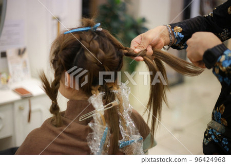 Male hairdresser tying woman's hair Male hairdresser tying woman's hair 96424968
