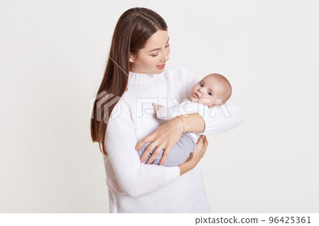 Closeup portrait of beautiful European woman holding on hands her little daughter on white background. Family, love, lifestyle, motherhood and tender moments. Closeup portrait of beautiful European woman holding on hands her little daughter on white background. Family, love, lifestyle, motherhood and tender moments. 96425361