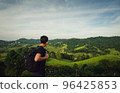 rear view of young man traveller with backpack  look at faraway of mountain view and tuscany 96425853