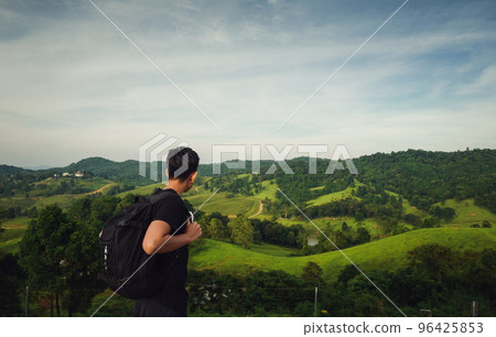 rear view of young man traveller with backpack look at faraway of mountain view and tuscany rear view of young man traveller with backpack look at faraway of mountain view and tuscany 96425853