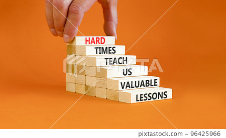 Lesson from hard times symbol. Concept words Hard times teach us valuable lessons on wooden blocks on a beautiful orange background. Businessman hand. Business lesson from hard times concept. 96425966