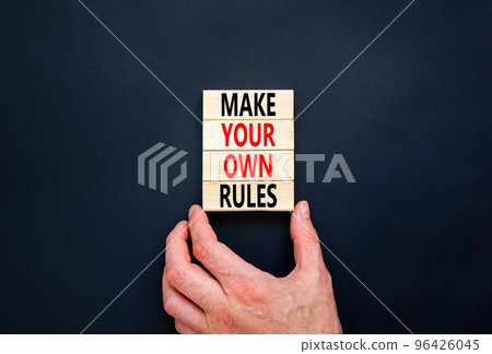 Make your own rules symbol. Concept words Make your own rules on wooden cubes. Beautiful black table black background. Businessman hand. Business motivational make your own rules concept. Copy space 96426045