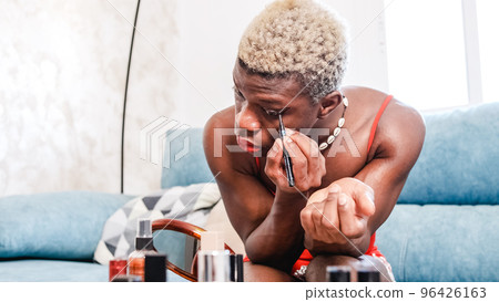 Black african man applying makeup at home Black african man applying makeup at home 96426163