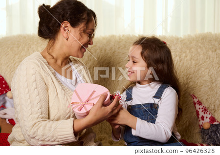 Loving caring mother and daughter enjoy Christmas holidays together at home, exchanging beautiful Xmas presents while sitting close to each other, on a comfortable sofa. Happy family relationships. Loving caring mother and daughter enjoy Christmas holidays together at home, exchanging beautiful Xmas presents while sitting close to each other, on a comfortable sofa. Happy family relationships. 96426328
